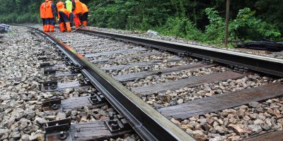 Workers in orange  raincoats repair railroad on rainy day